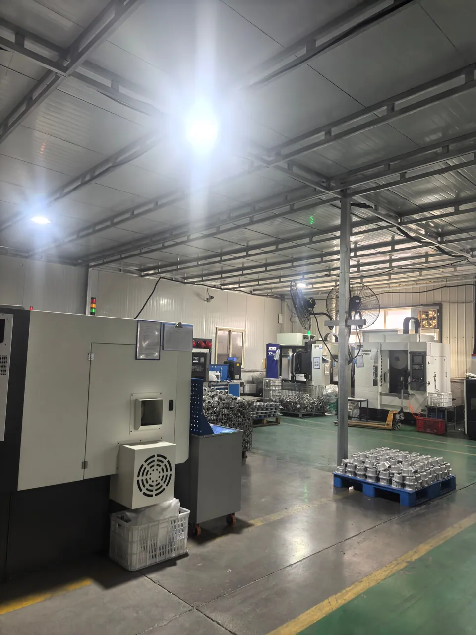 Metal components on handling pallets beside machining equipment